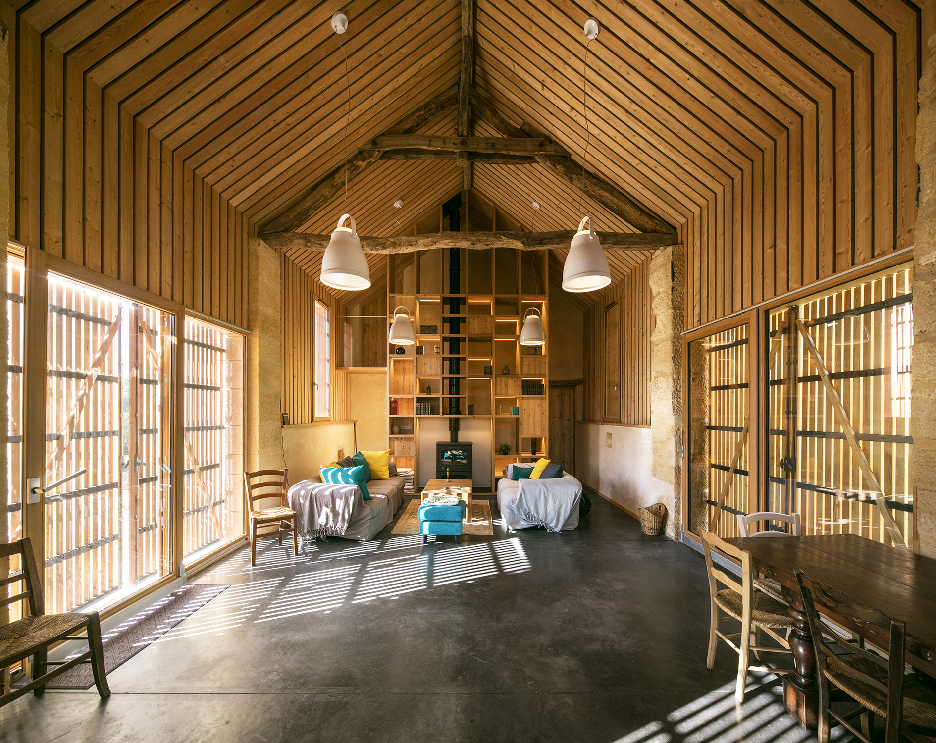 Pour accentuer la hauteur de la pièce principale, faire un effet cathédral, les parties verticales et les plafonds sous rampant ont été réalisés avec la même finition en tasseaux de bois ajourés. / Edouard Decam - CoCo architecture - Granges réhabilitées, Beynac et Cazenac, 2021