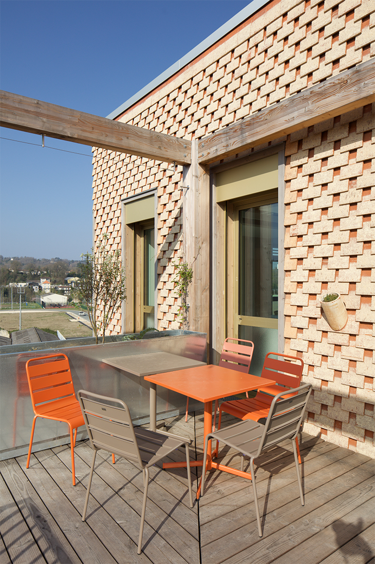 Terrasse du dernier niveau avec la vue sur le grand perigueux. La ligne de démarcation laissé par les pigments, crée un jeu de nuance en damier sur la façade / Edouard Decam - CoCo architecture et Scapa architecte - L'oustaL, Périgueux, 2025