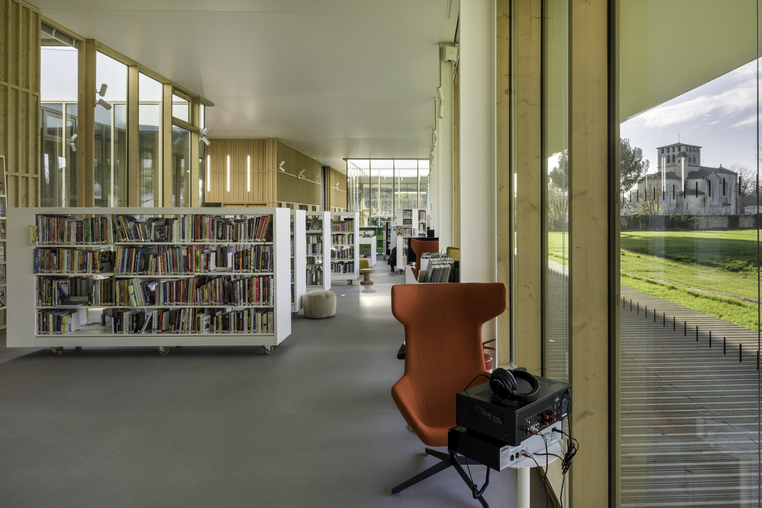 Les espaces largement ouverts et traversants, se prolongent sur l'extérieur grâce à la façade largement vitrée qui offre des vues sur le parc, la chartreuse et l'église romane totue proche / Jean-François Tremege – Marjan Hessamfar et Joe Vérons architectes – Pôle culturel et festif BOMA, Saint-Denis-de-Pile, 2021