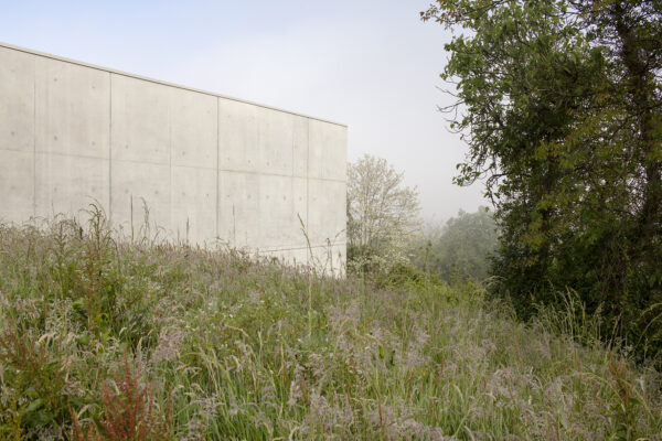 La façade en béton brut contraste et dialogue avec l’environnement de verdure / © Agnès Clotis - MOON SAFARI - Cuisine centrale Bidache - 2024
