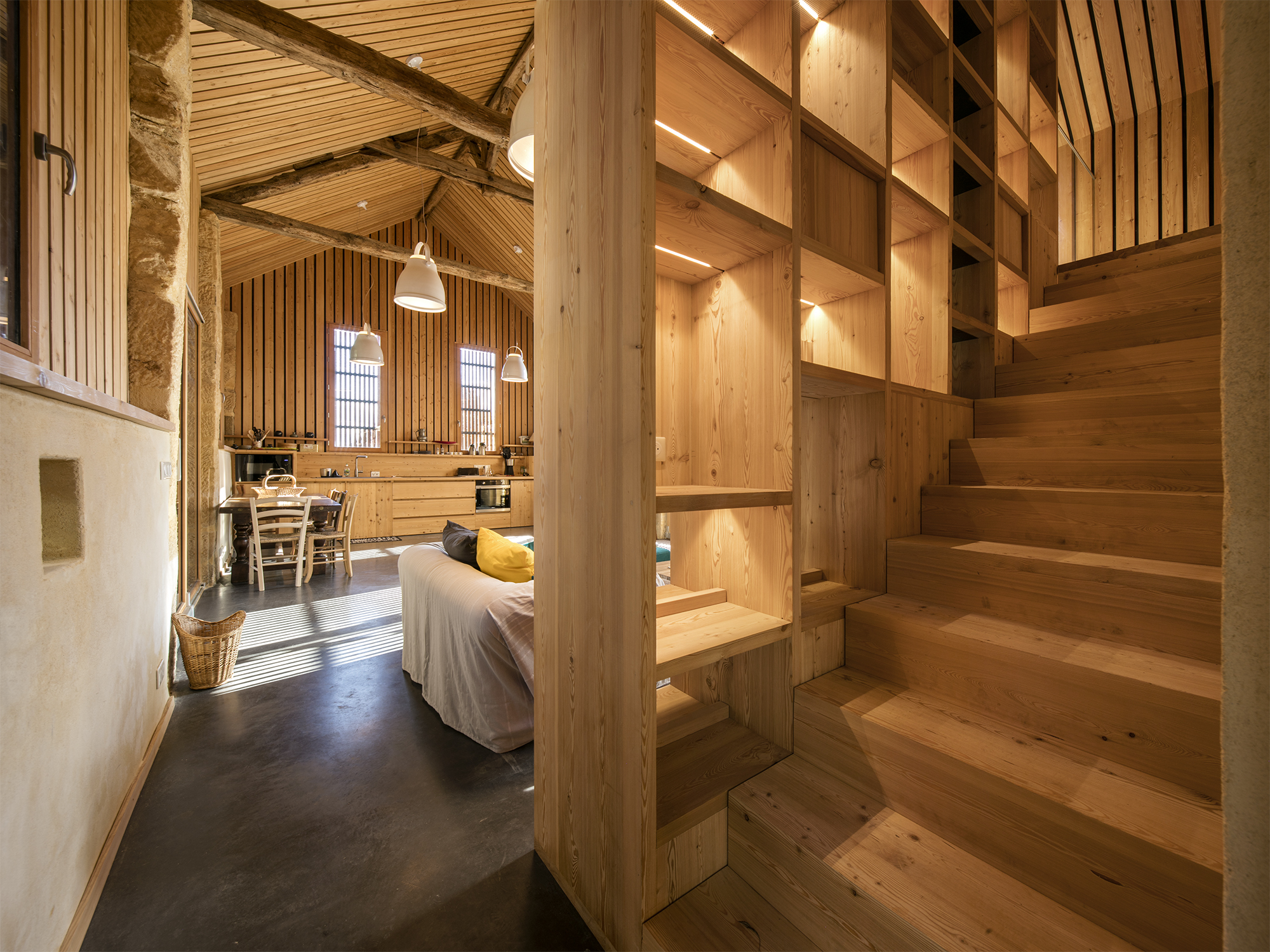 Une bibliothèque toute hauteur sert de support à l'escalier soigneusement calepiné sur le rythme des étagères. / Edouard Decam - CoCo architecture - Granges réhabilitées, Beynac et Cazenac, 2021
